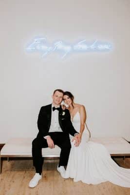 bride and groom sitting on a white cushion bench with a neon light above them, The Alfond Inn, Orlando, FL