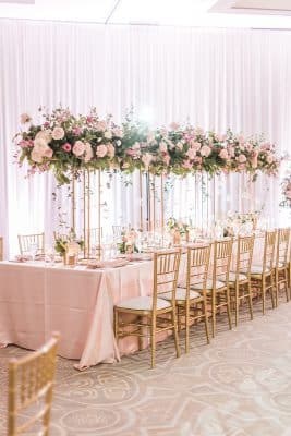tall pink floral centerpieces down the center of the long rectangular table, pink tablecloth, gold chairs, pink curtain on the wall, The Alfond Inn, Orlando, FL