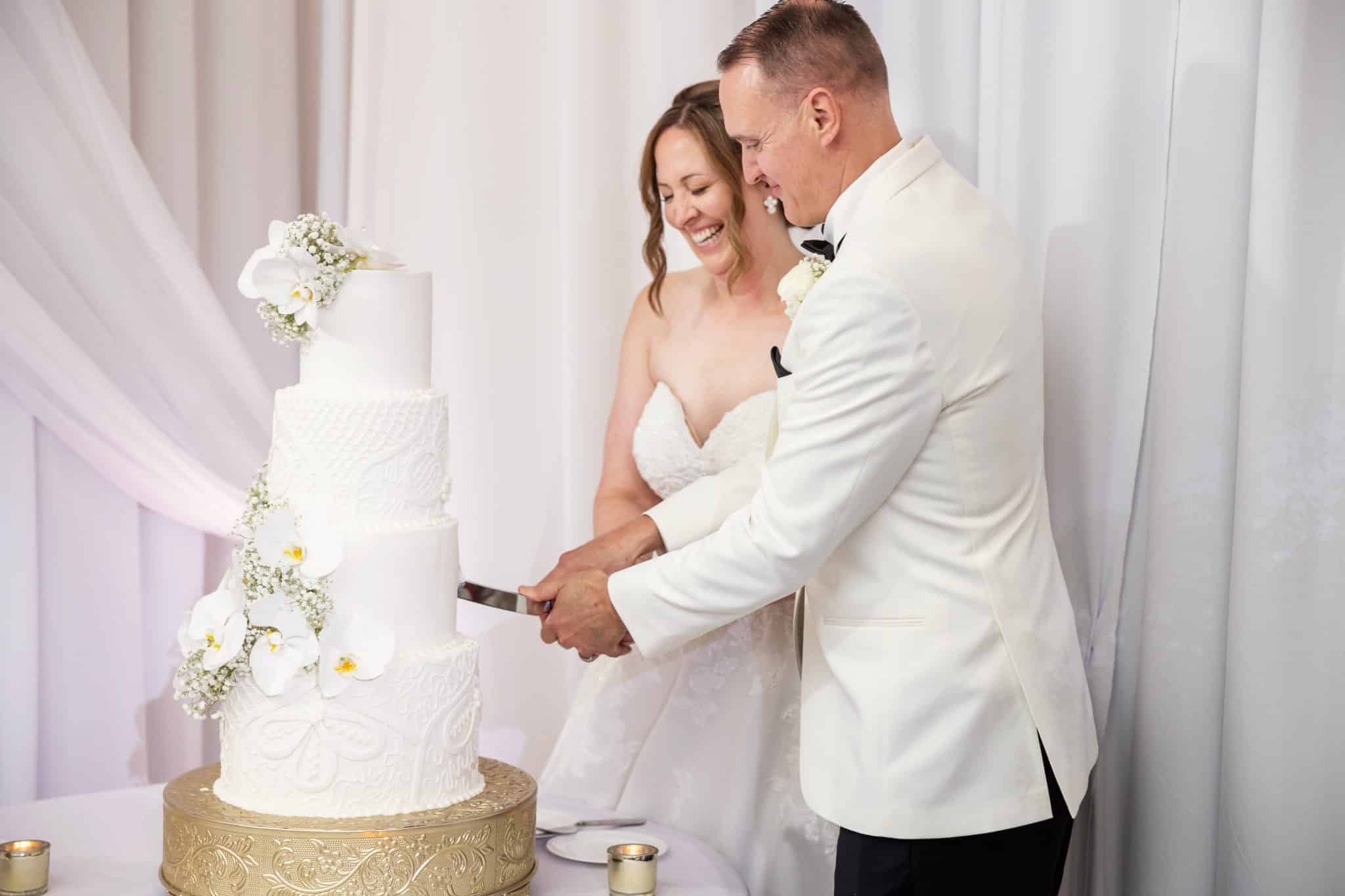 couple cutting their 4 tier white cake 