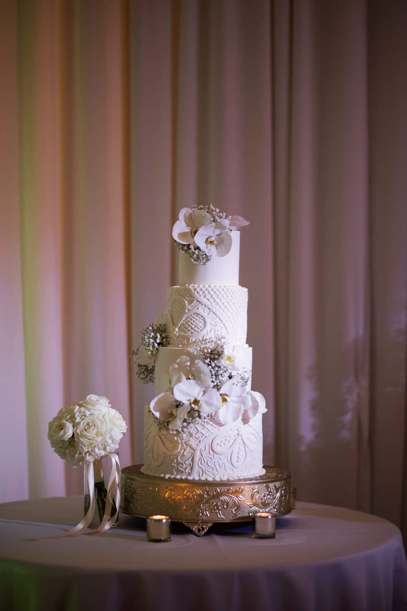 four tier white cake with bold designs of light purple colors