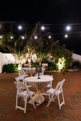 small cocktail tables, white chairs, outdoors on a patio, night time, Orlando, FL