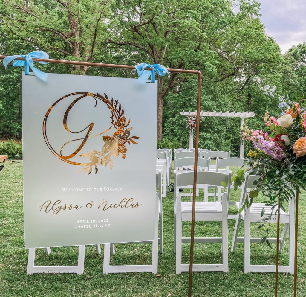 welcome sign for a wedding, ceremony set up with white chairs, floral bouquet at the end of the aisle, Petal + Grain Designs, Orlando, FL