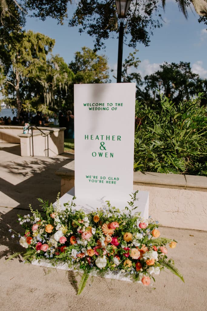 wedding sign in green text, large floral arrangement laying in front of the sign, Orlando, FL