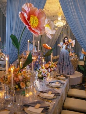woman in a blue dress playing a violin, table set for dinner, large plastic floral decorations, Orlando, FL