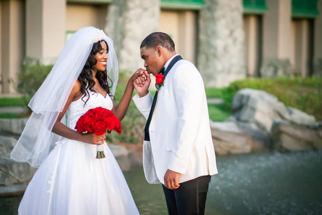 bride and groom outside, red floral bouquet, groom kissing her hand, Dream Day Digital, Orlando, FL