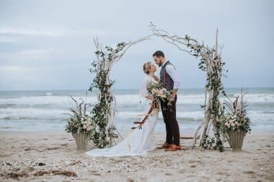 bride and groom embracing under the arch, covered in greenery, oceanfront, Orlando, FL