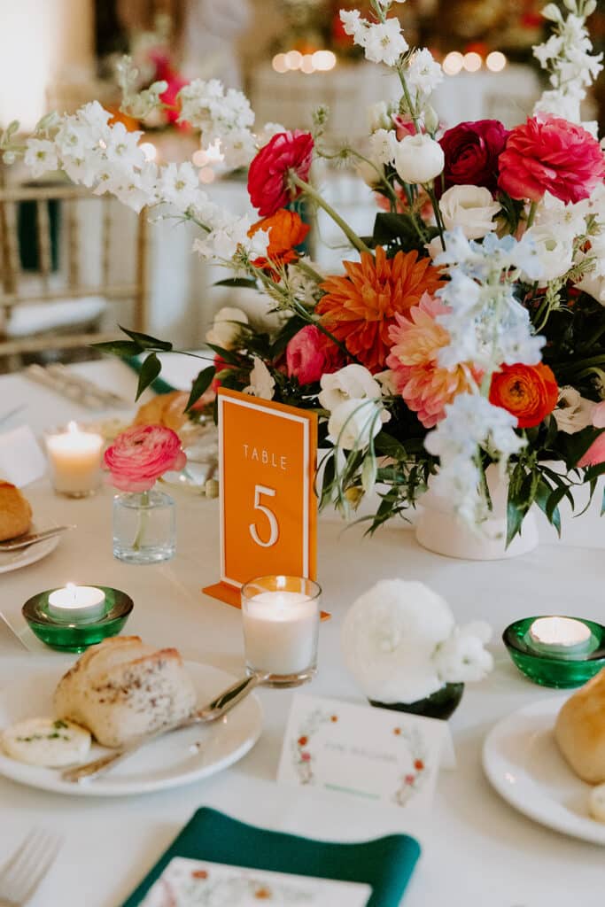 tablescape, red and white flowers as centerpieces, green napkins, white plates, votive candles, name cards, Petal + Grain Designs, Orlando, FL