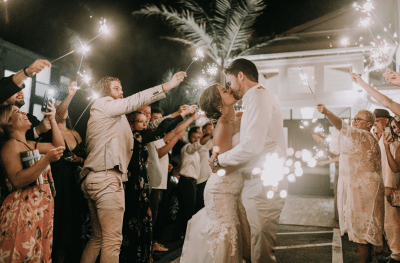 bride and groom kissing while their guests say farewell and congratulations with sparklers, Orlando, FL