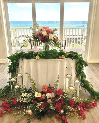 head table, round, in front of the windows, leading to the patio, garland wrapped around with red and white flowers, Orlando, FL
