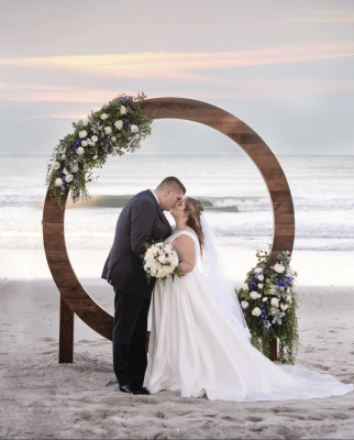 circular wooden pergola set on the beach, bride and groom kissing under it, beach front, Harbour House Oceanfront, Orlando, FL