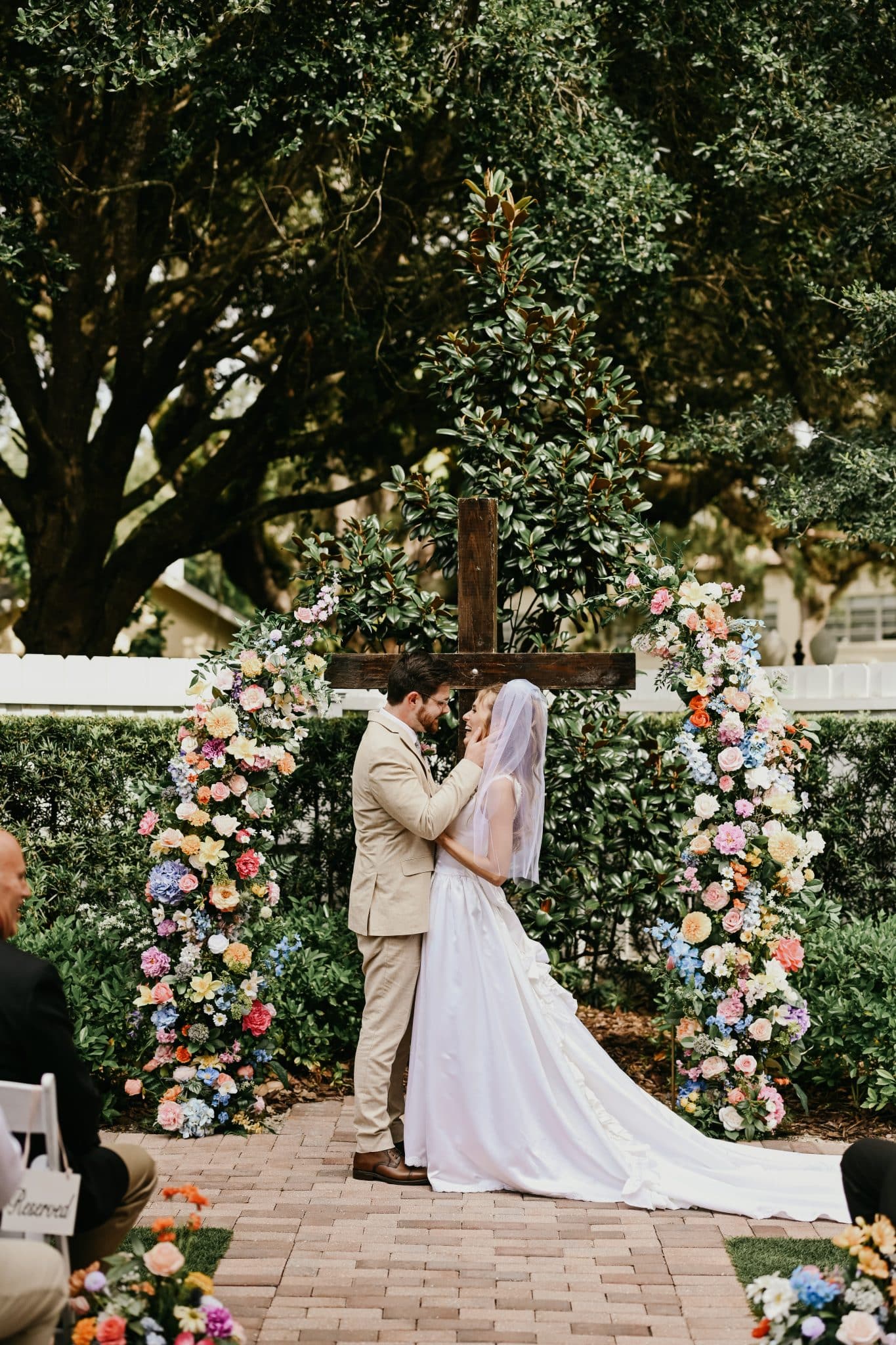 bride and groom getting married in front of gorgeous colorful florals on an open arch 