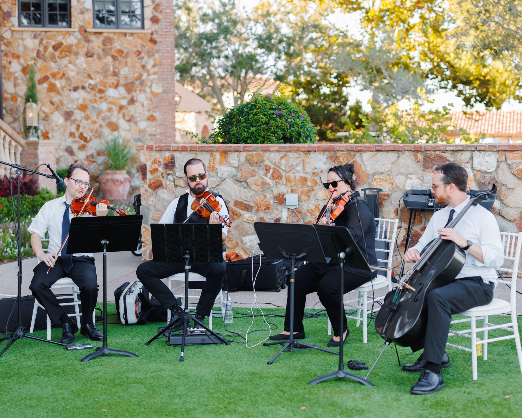 image of live musicians playing a wedding with a gorgeous brick wall behind them and greenery 