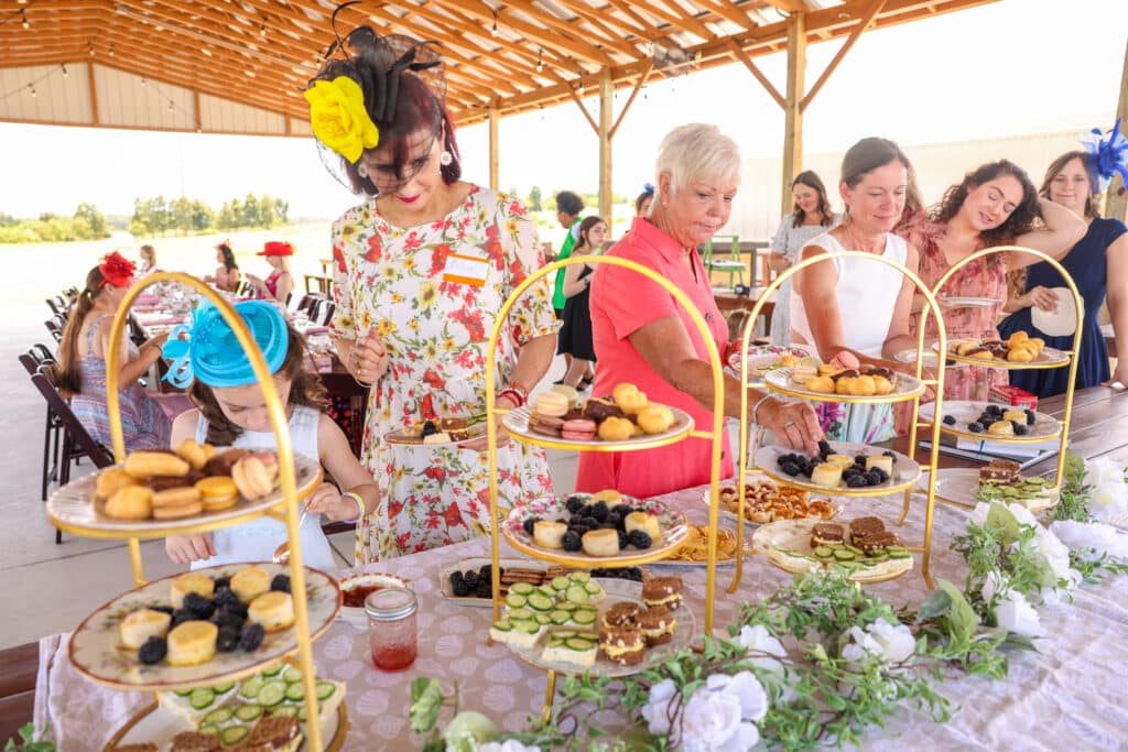 guests gathered at the tea party, dessert table filled with delicious desserts on stands, outdoor pavilion, Orlando, FL