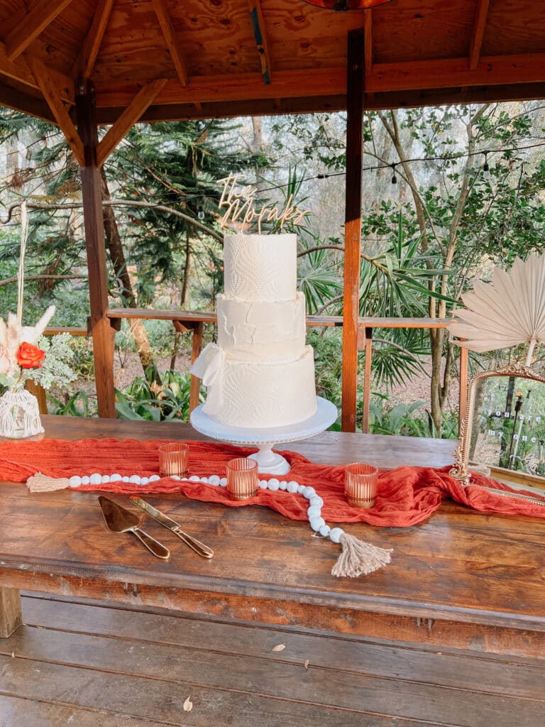 three tiered white cake with a couple's name on top, under a pavilion outdoors, Orlando, FL