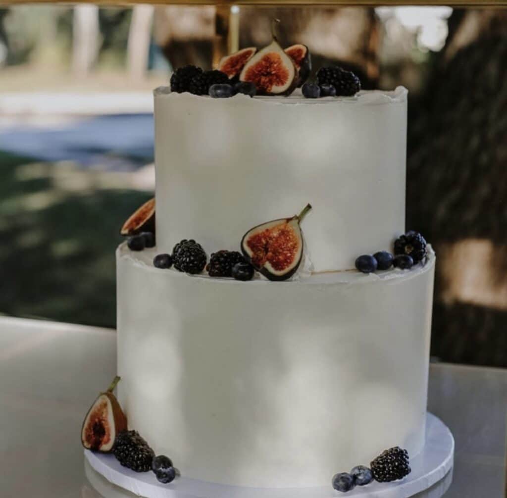 two tiered wedding cake with dates and figs at the base of each level, outside on a table, Orlando, FL