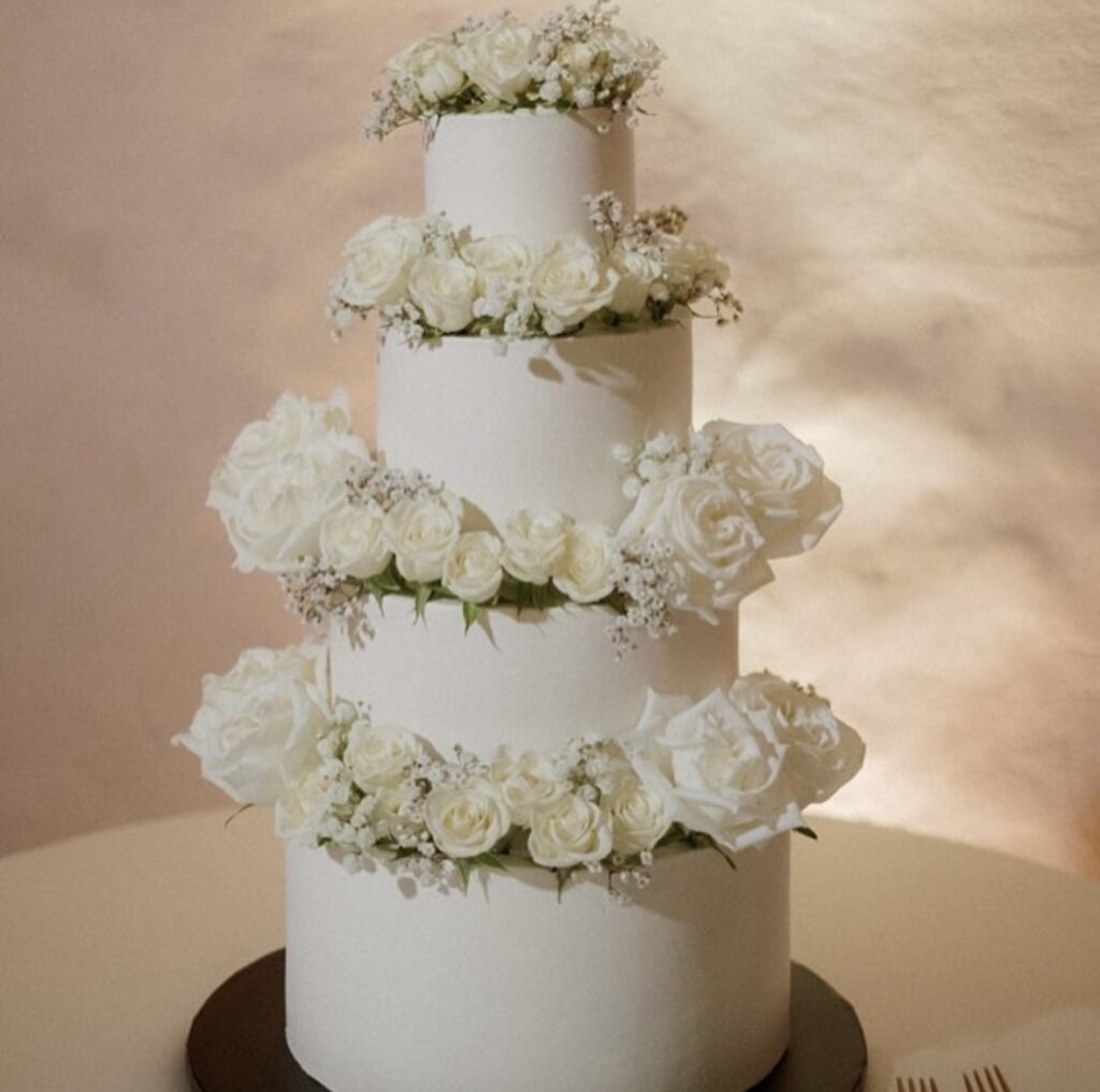 close up of a four tiered cake, white frosting, adorned by white flowers at the top of each tier, Orlando, FL