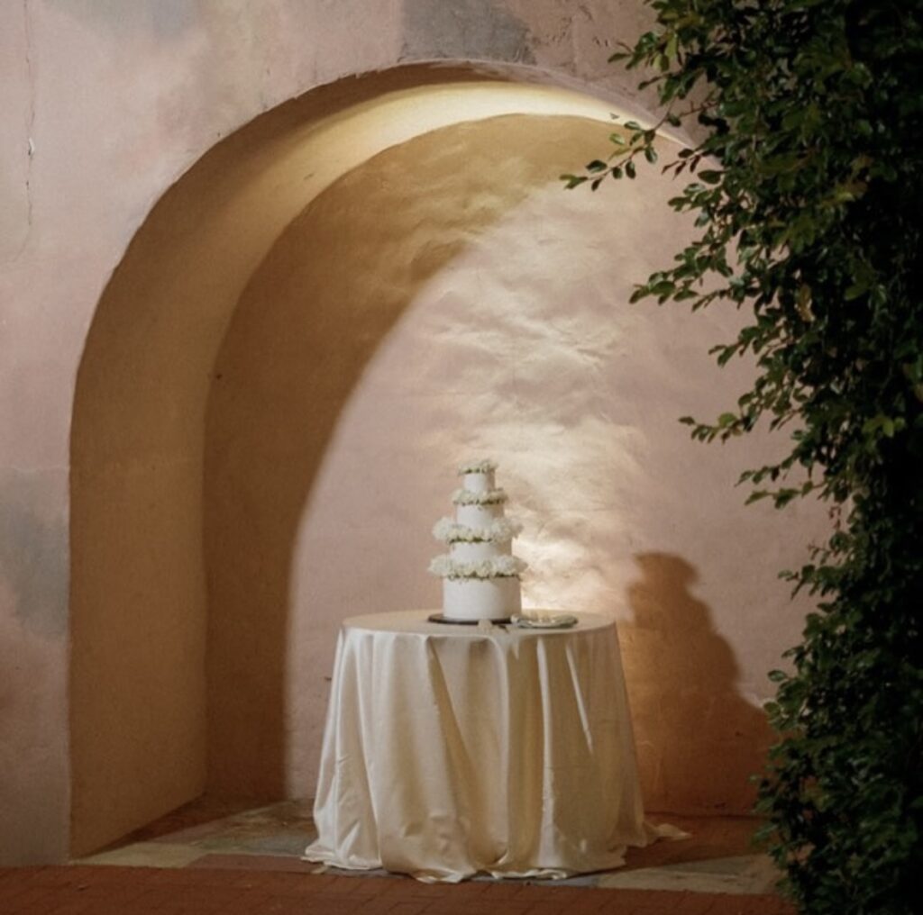 archway, outside, four tiered white wedding cake on a table with a white tablecloth, Orlando, FL