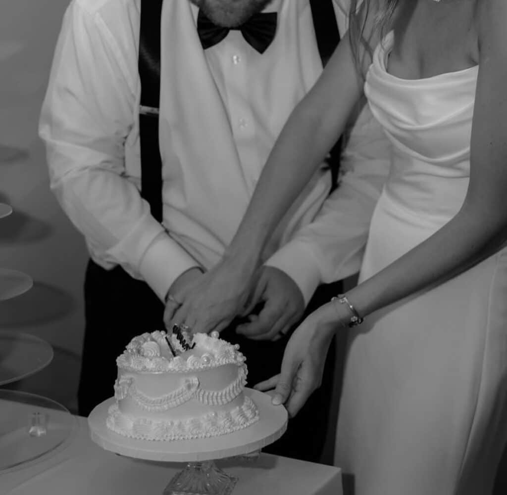 black and white photo of a bride and groom cutting into their cake, Iced by Taylor, Orlando, FL