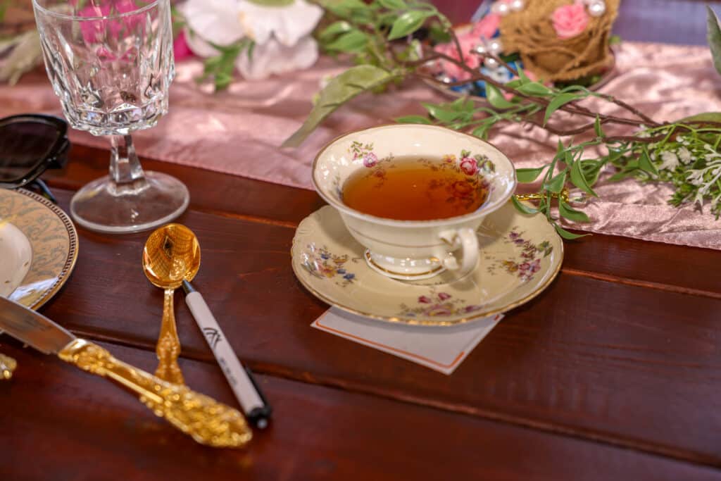 cup of tea in a white tea cup on a floral saucer, pink runner, wooden table, Orlando, FL