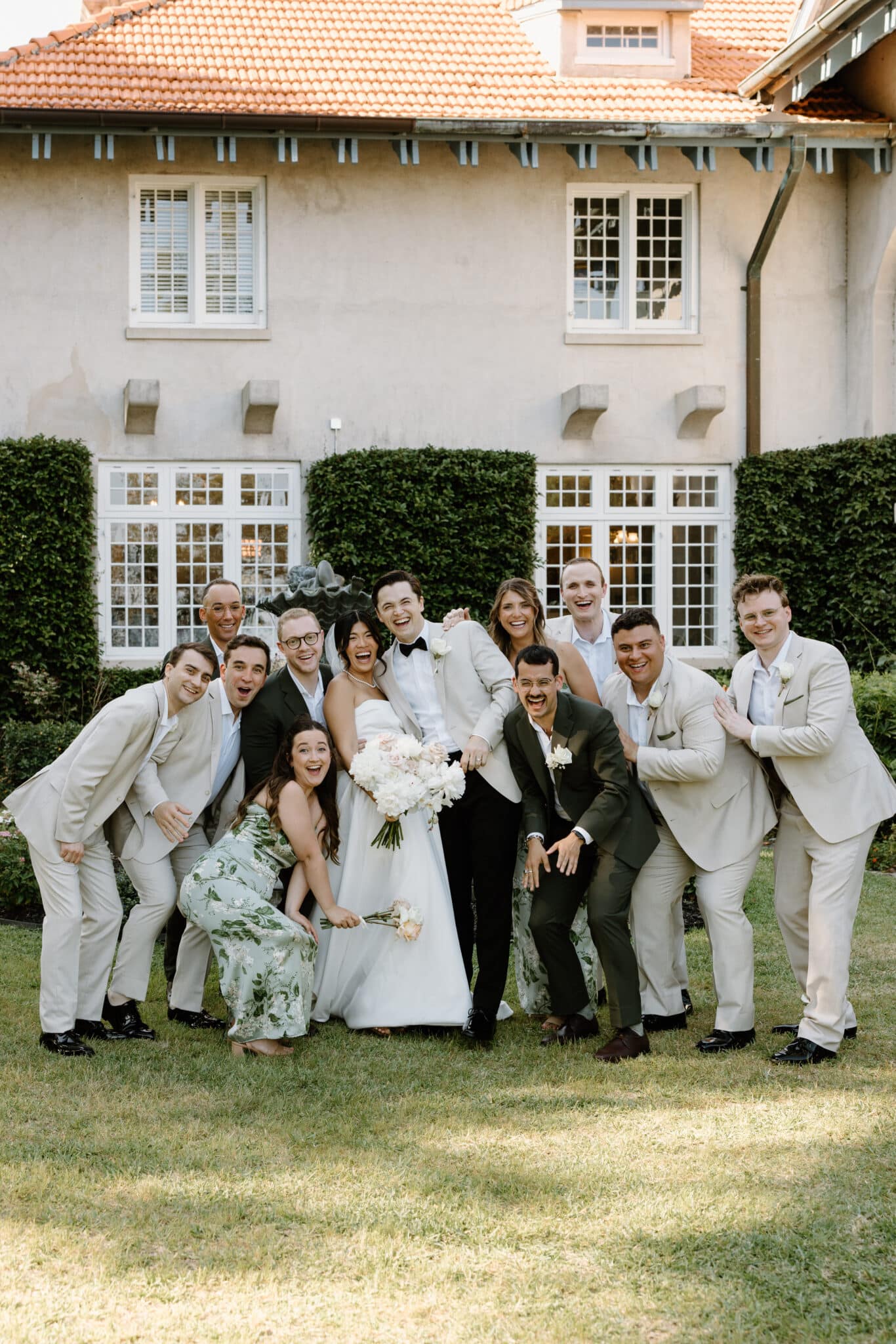 couple posing with bridal party in front of The Sydonie Mansion for their elegant outdoor wedding