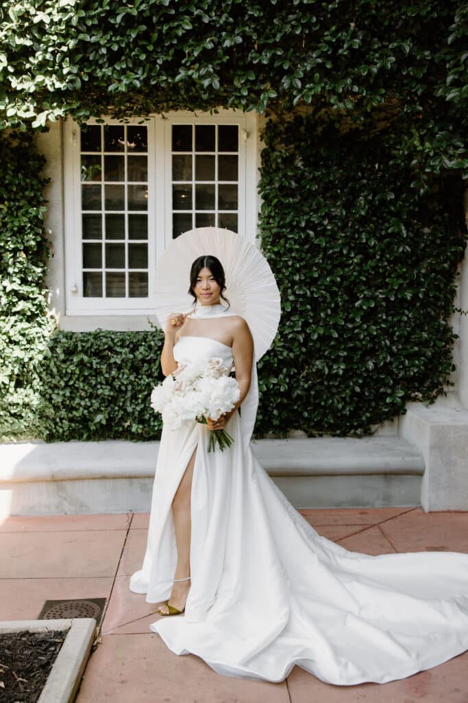 Bride posing with bouquet and a parasol as a prop