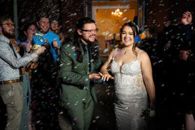 bride and groom surrounded by their wedding guests, outside, lights sparkling around, Orlando, FL