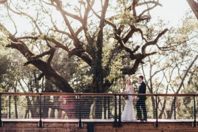 bride and groom standing on the bridge, lots of trees around, Orlando, FL