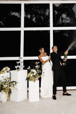 bride and groom popping the champagne, indoors, large window with nine panes, Uliana Estate, Orlando, FL