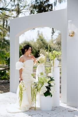 bride in her wedding gown, outdoors, wedding reception, white flowers with greenery on display, Uliana Estate, Orlando, FL