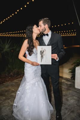 bride and groom kissing while holding a sketch of themselves, Orlando, FL