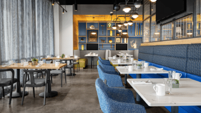 Blue upholstered booth seating and modern dining area inside Aloft Orlando Lake Nona, a colorful mid-range hotel wedding venue in Lake Nona, Central Florida