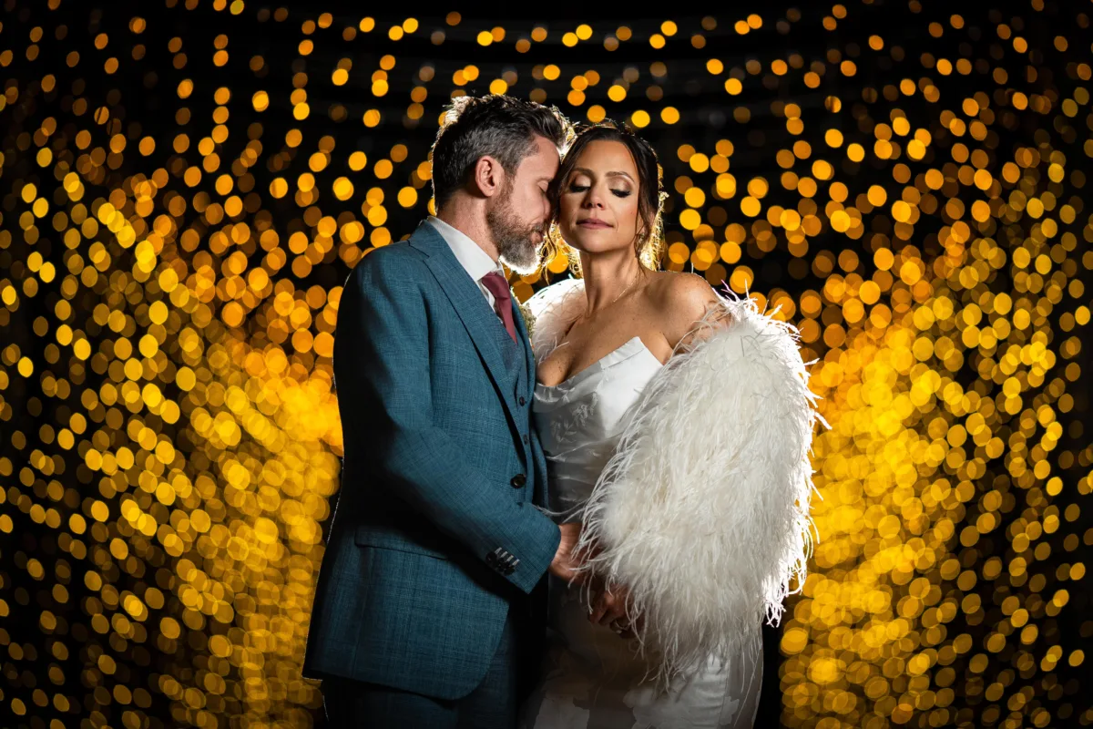 cinematic bride and groom in a dramatic portrait with bokeh lights surrounding them
