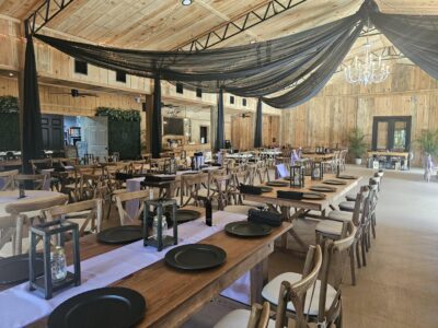 indoor pavilion, wooden structure, black material hanging from the ceiling, long tables, wood chairs, black plates, lanterns and candles as centerpieces, Orlando, FL