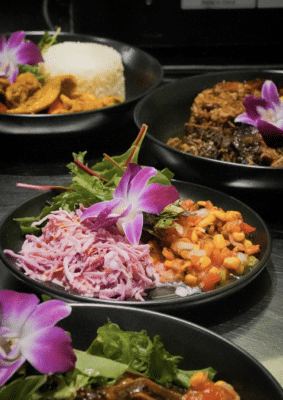 several plates of food on black plates or black bowls, adorned with orchid flowers, Orlando, FL