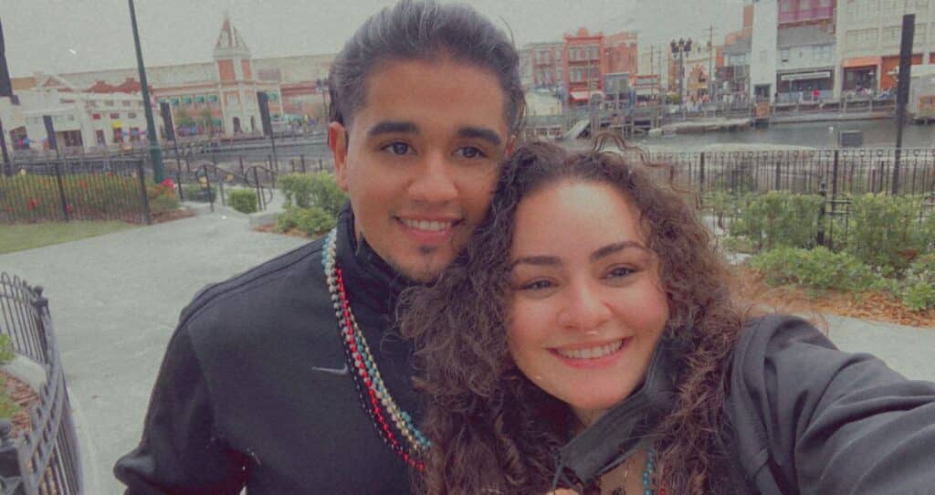 Selfie of a couple wearing all black with colorful beaded necklaces. 