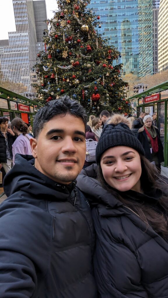 Couple selfie in front of a Christmas tree with red and gold adornments. 