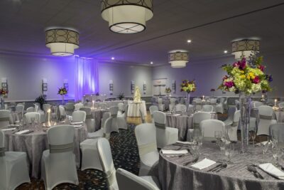 ballroom set for an event, silver tablecloths, round tables, grey chairs, tall floral centerpieces, Orlando, FL