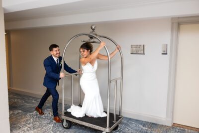 Groom pushing a hotel cart with the bride on board, through the hotel hallway, Crowne Plaza Orlando Downtown, Orlando, FL