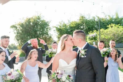 bride and groom kissing, wedding guests and wedding party around them, Orlando, FL