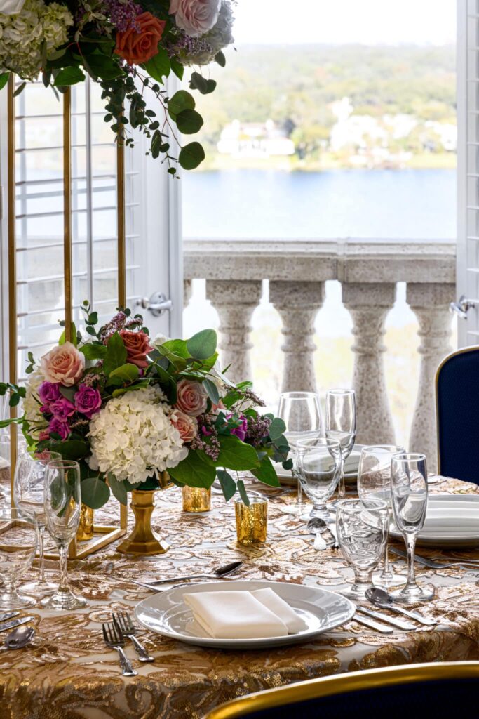 dinner table set with glassware, plates, flatware, floral centerpiece, view of the water, Orlando, FL
