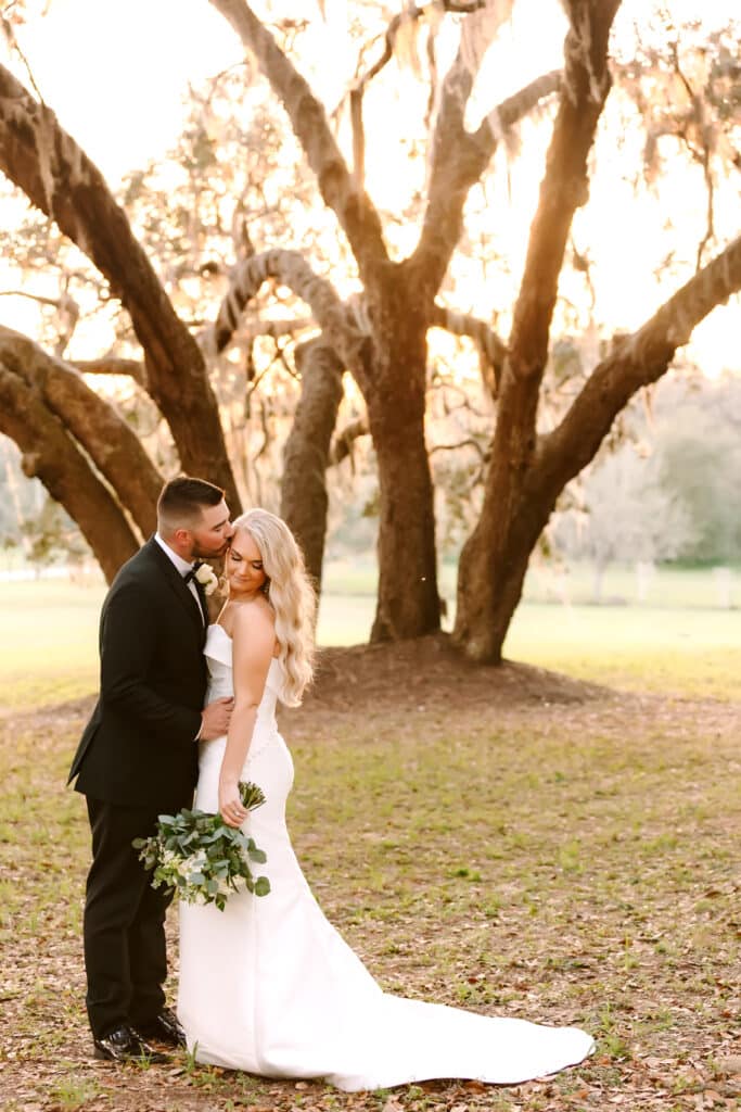 bride and groom kissing near trees, outdoors, sunset, Orlando, FL
