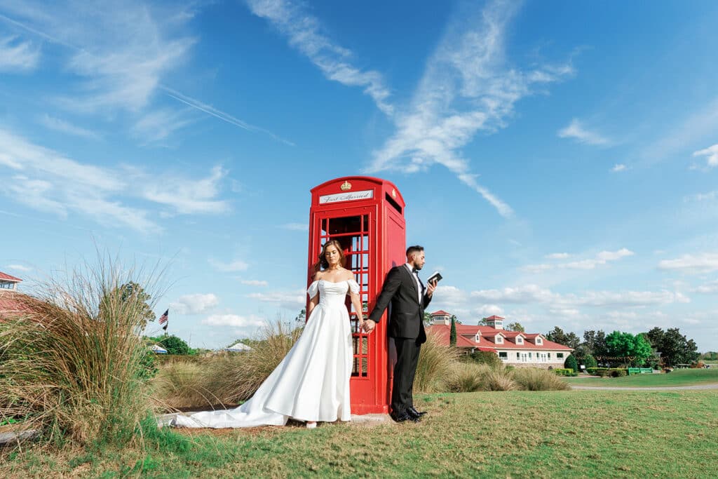 Bride and groom standing in front of a red photo booth, blue skies, Orlando, FL
