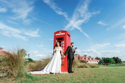 Bride and groom standing in front of a red photo booth, blue skies, Orlando, FL