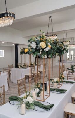 indoor event, long tables, white tablecloths, clear plates, green napkins, gold chairs, white and yellow flower arrangements, Orlando, FL