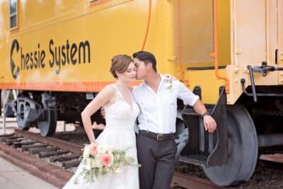 close up of the bride and groom walking by the train car, groom kissing his bride on the cheek, Orlando, FL