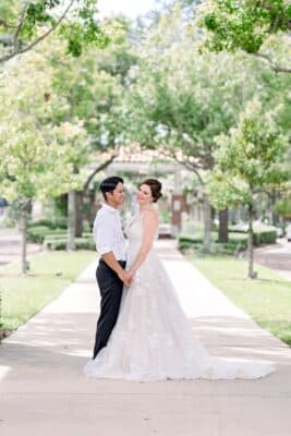 wedding couple in their wedding attire standing outside on the sidewalk, gazebo behind them, trees, Orlando, FL