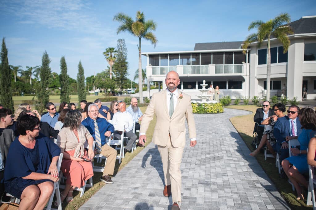 man walking down the aisle at the wedding ceremony, tan suit, stone pathway, Rockledge Country Club, Orlando, FL