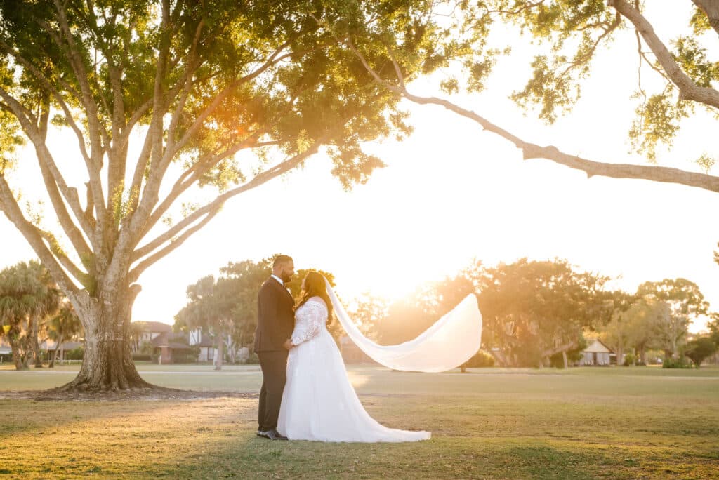bride and groom standing on the lawn, veil blowing in the wind, sunset, Orlando, FL
