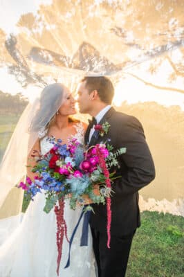 bride and groom kissing, outdoors, large purple and blue floral bouquet, Rockledge Country Club, Orlando, FL