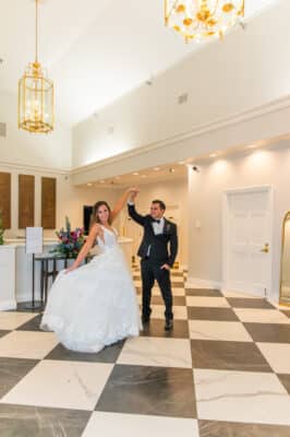 bride and groom twirling around, indoors, black and white checkered dance floor, Rockledge Country Club, Orlando, FL